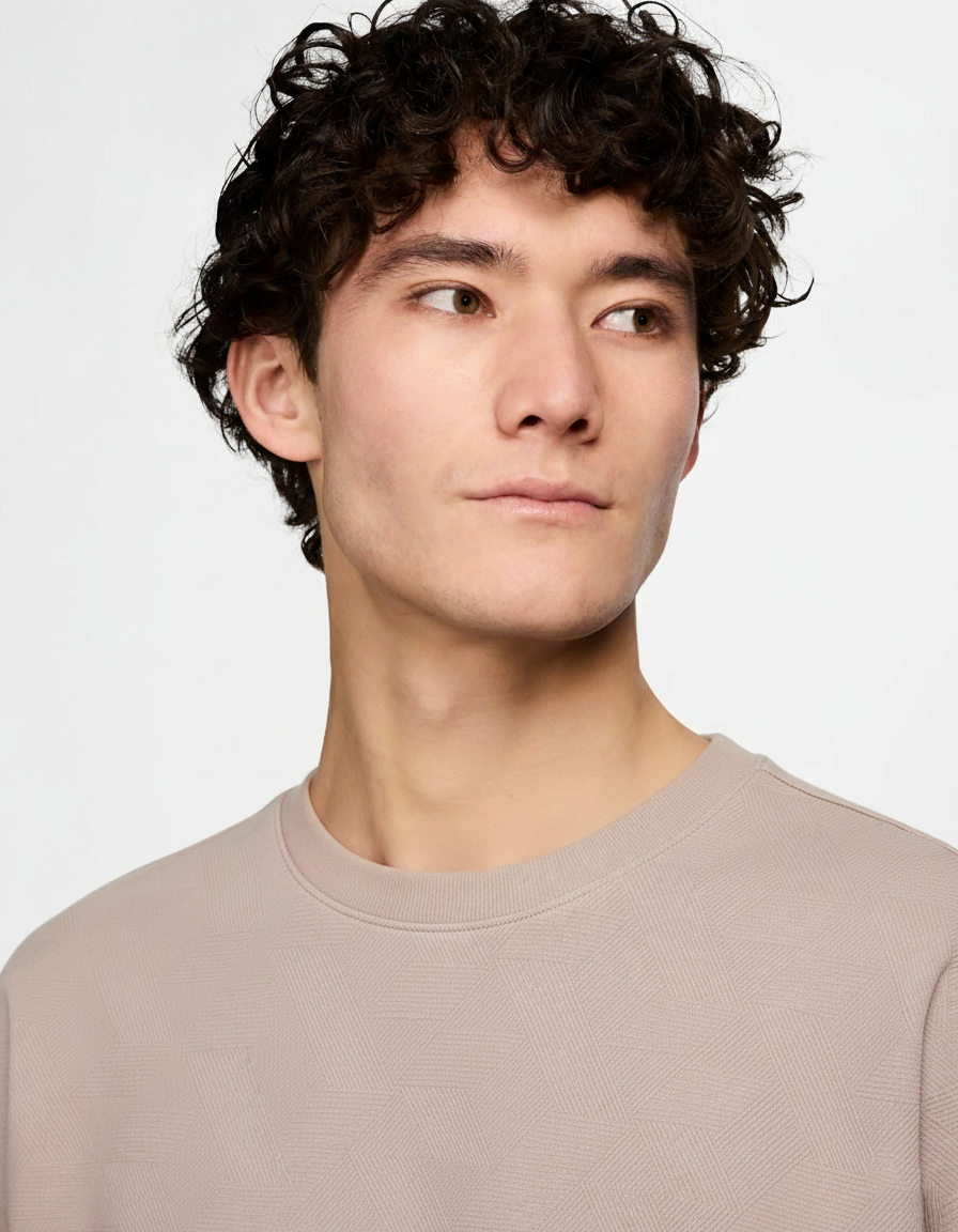 Man wearing a beige sweater against a plain background